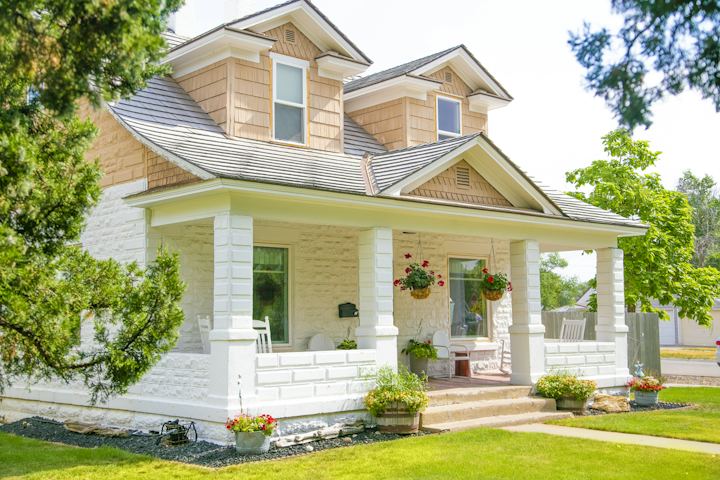 White and tan house with a covered front porch and dormer windows