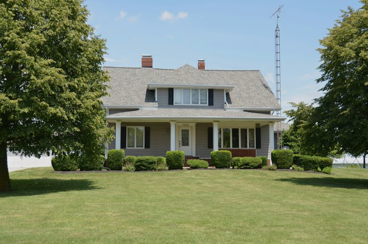 Rural farmhouse with a wide green lawn and trees